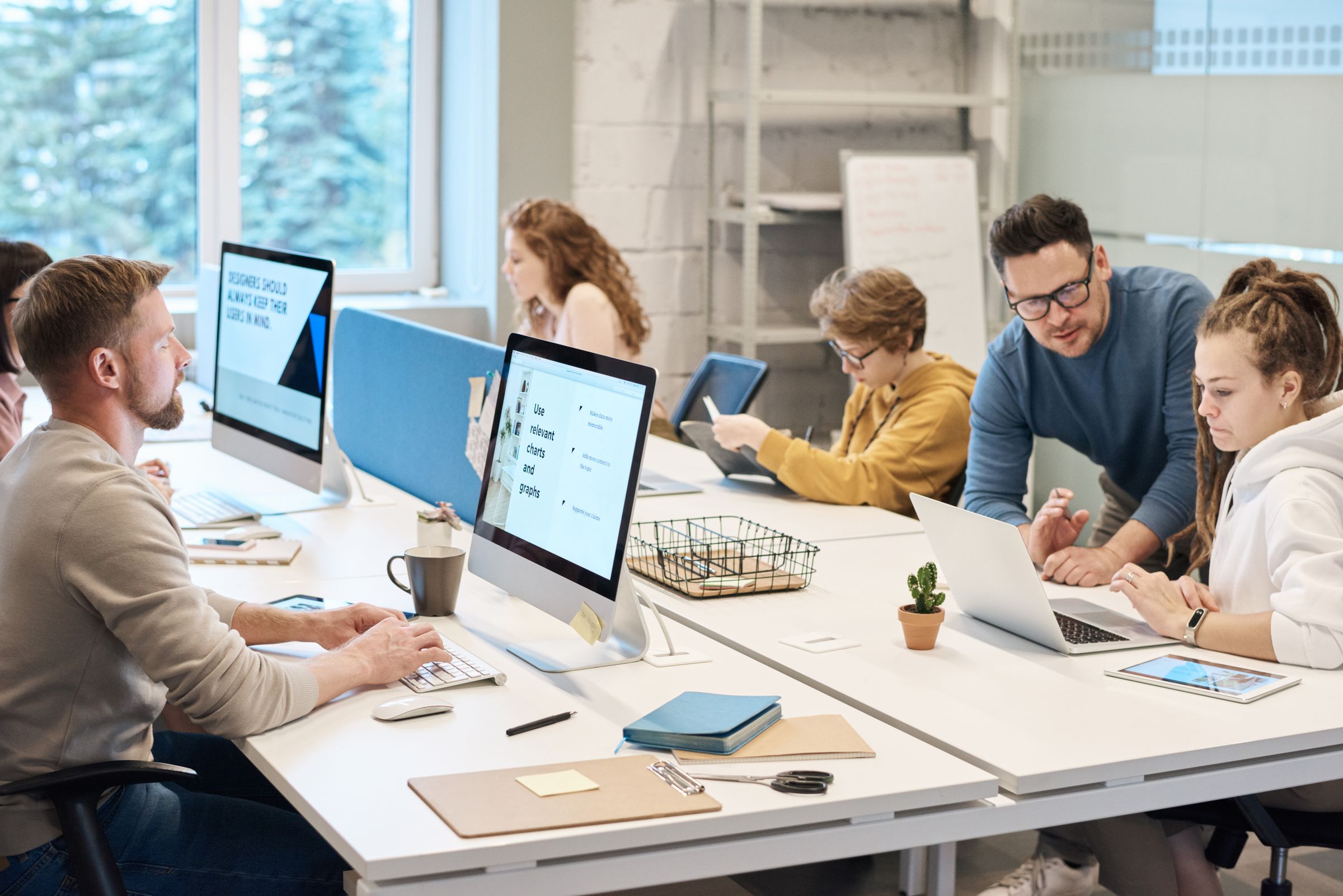 A team at work across desks and screens in a bright open-plan office